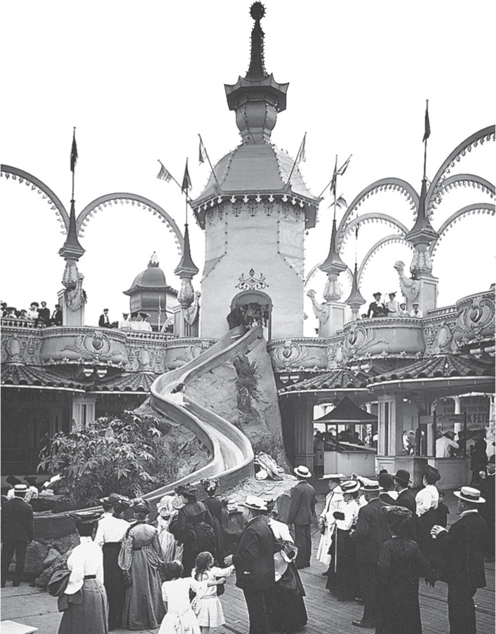 Photo shows well-dressed visitors at an amusement park slide.