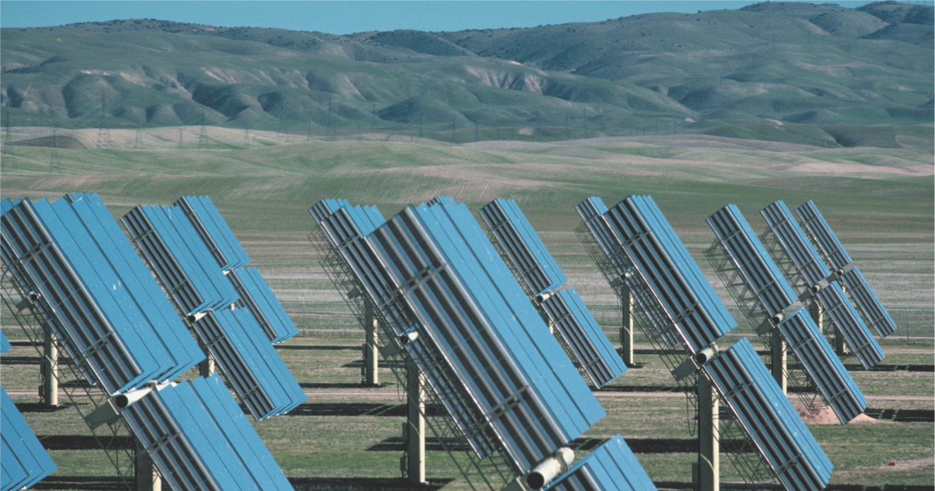 photo: in the desert, rows of mirror-like solar collectors are angled toward the sun.