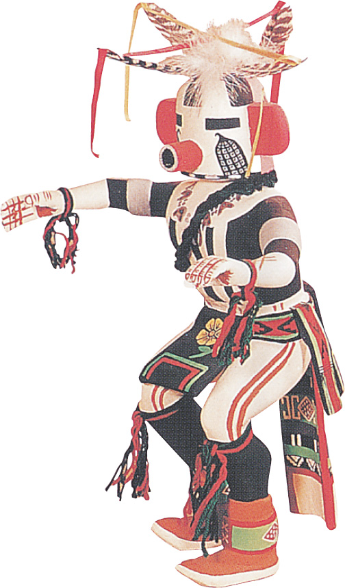 A Kachina doll wears a colorful costume including tassels in the knees and wrists, and a mask with large ears and nose, narrow eye slits and an elaborate feather headdress.