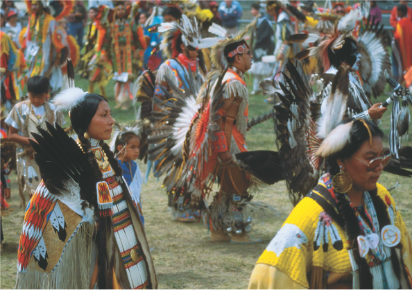 Photo shows present-day Native Americans at a celebration wearing traditional feather headdresses, bead jewelry and facepaint.