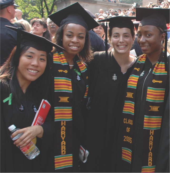 Photo of college graduates wearing black caps and gowns with colorful strips of cloth draped over their shoulders.
