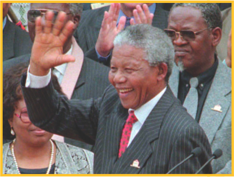 A photo: Nelson Mandela waves and smiles.