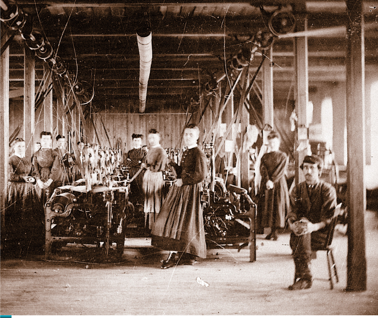 In a photo of a mill, women
workers stand by large textile machines.