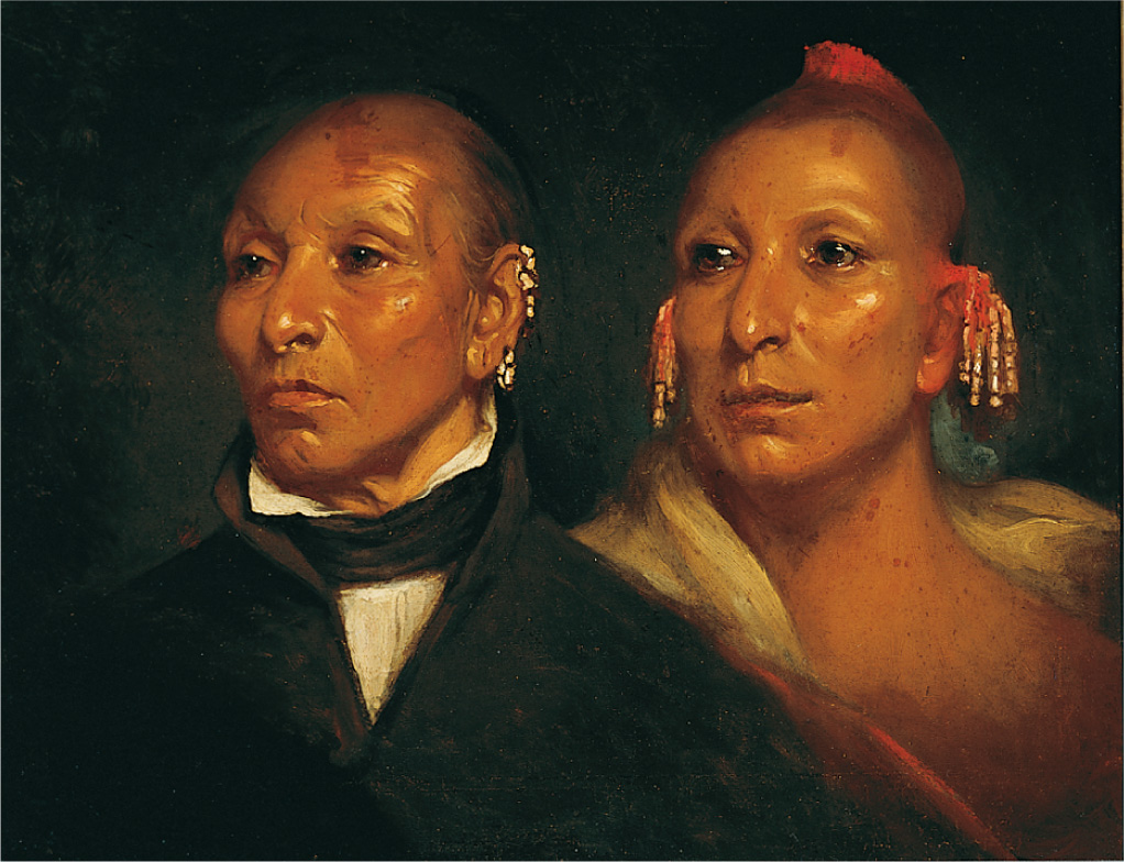 A portrait of two Native American men. The one on the left wears a dark suit, while the one on the right wears a native robe.