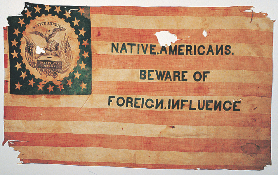 A banner with stars and stripes like the American flag reads Native Americans, beware of foreign influence.