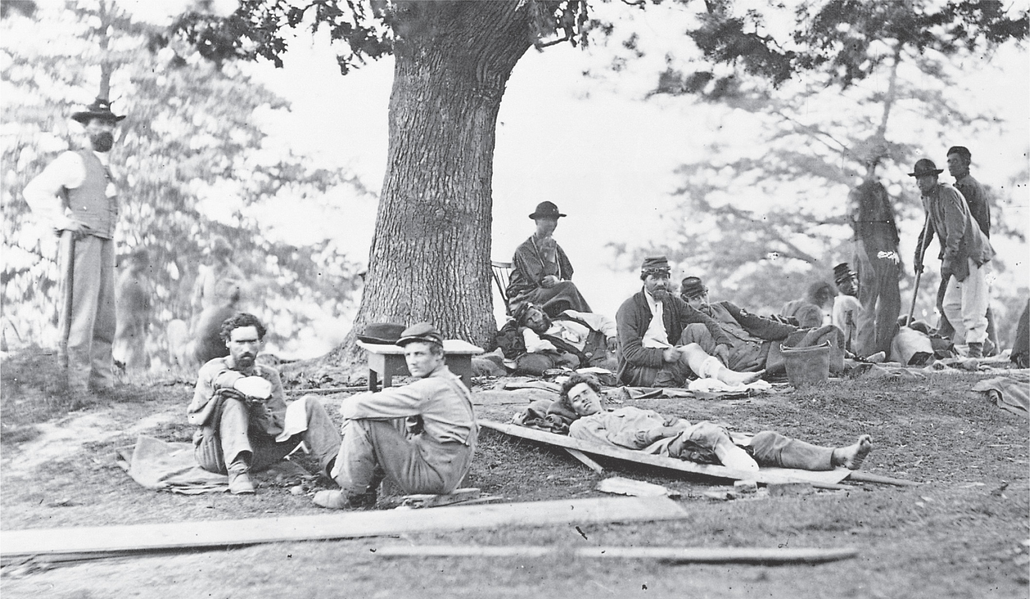 A photo: Union soldiers, some wounded, relax under a tree.