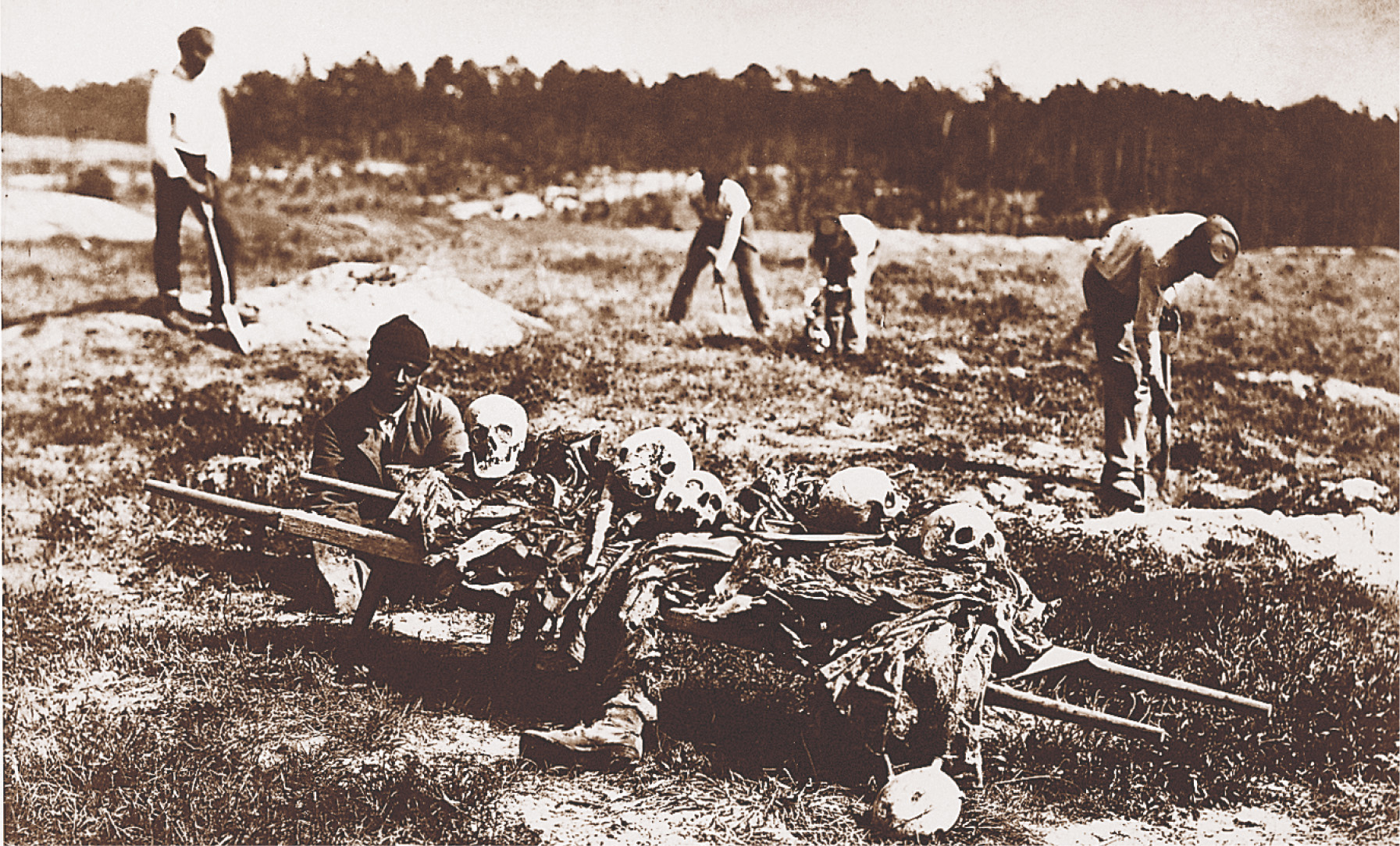 In a photo, African-American men load human skulls and body parts onto a cart.