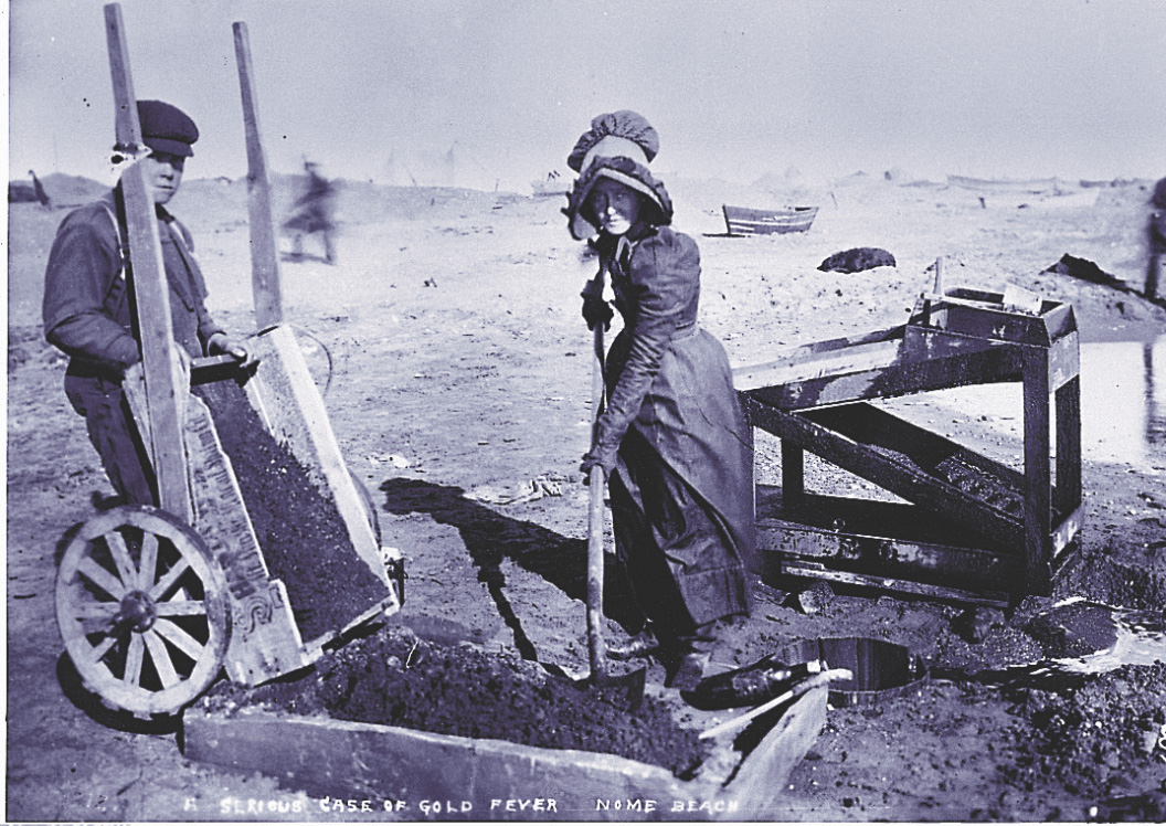 A photo: a woman shovels dirt into a sluice, while her teenage son pours more dirt into a wood box.