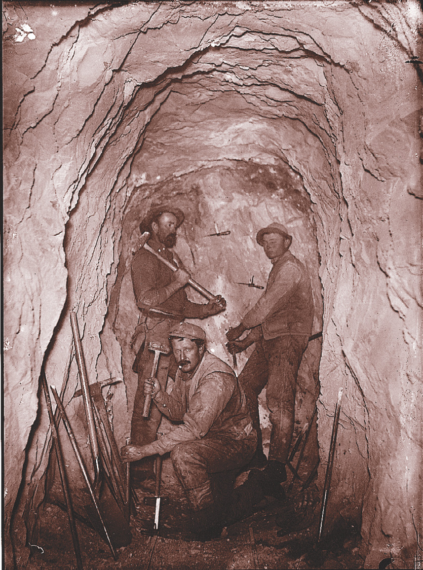 A photo: men work with picks in a gold mine.