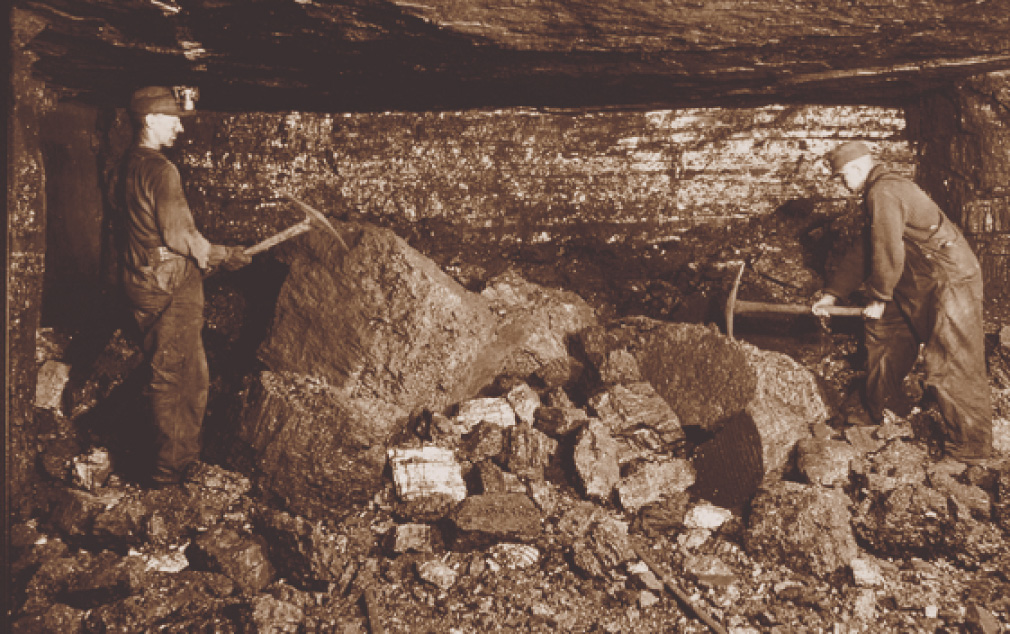 Photo: In a mine, a man strikes a rock with a pick