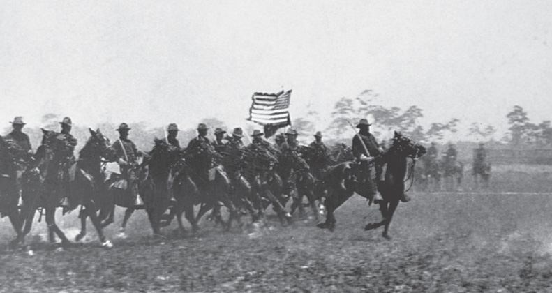 Photo: soldiers on horseback carry an American flag.