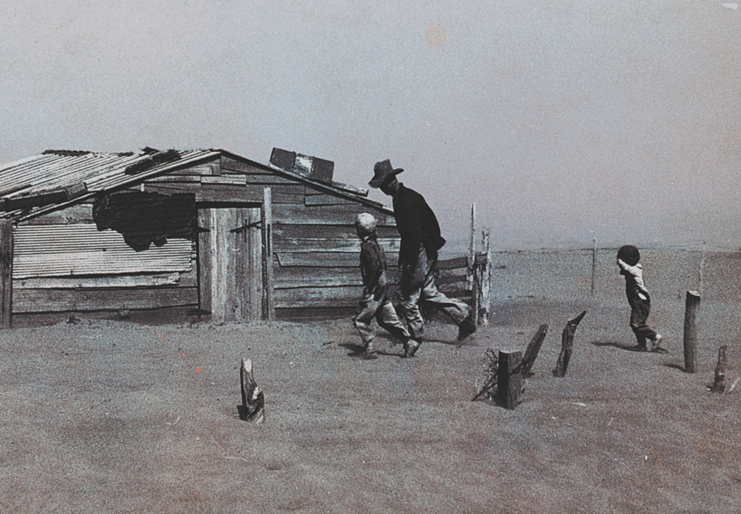 Photo: A man and two children run toward a shack on a flat plain