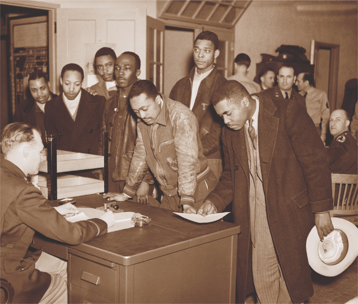 Photo: A half-dozen African American men cluster around a desk