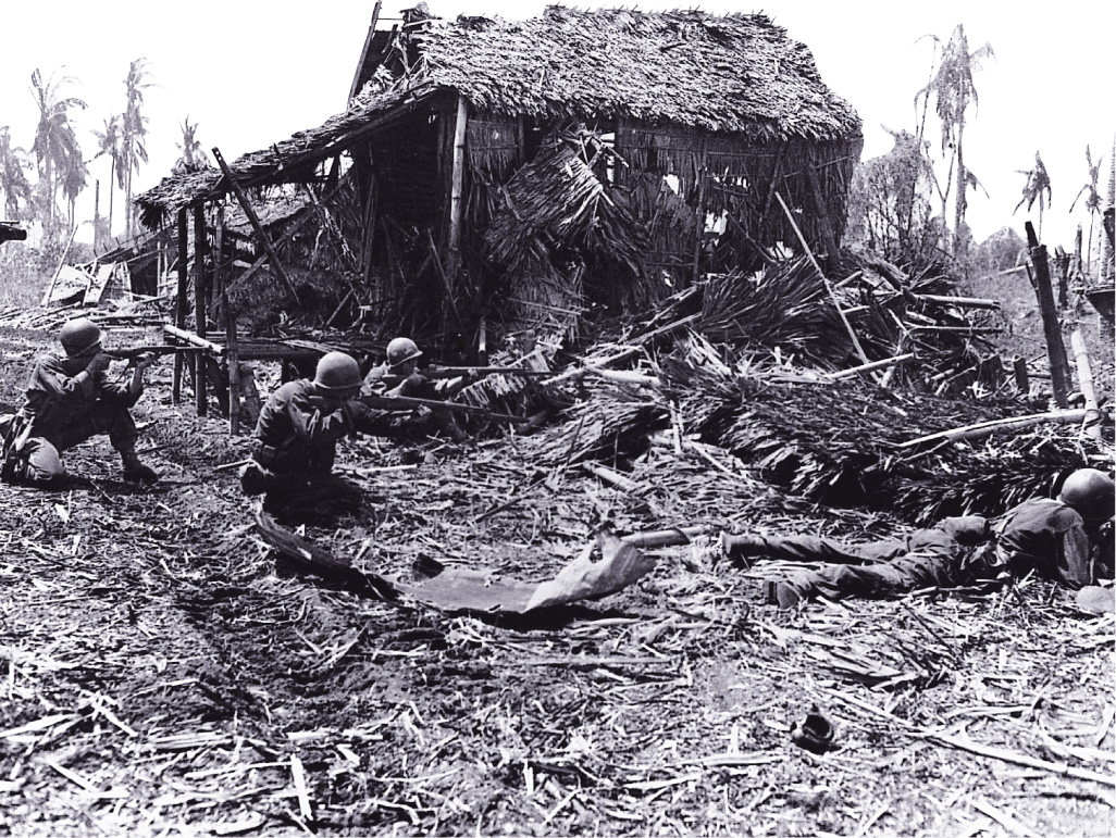 Photo: soldiers crouching with rifles behind a demolished shack