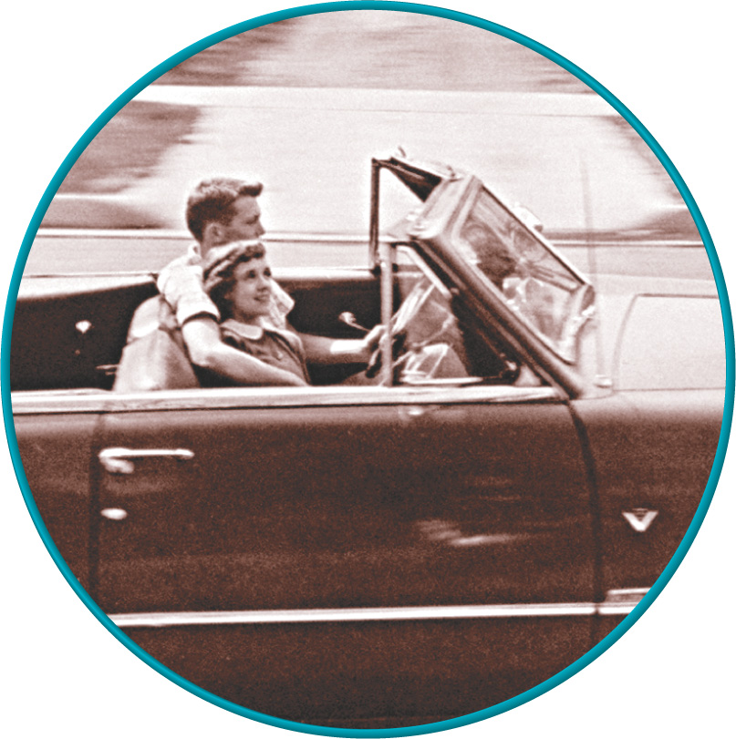 Photo: a young couple riding in a convertible