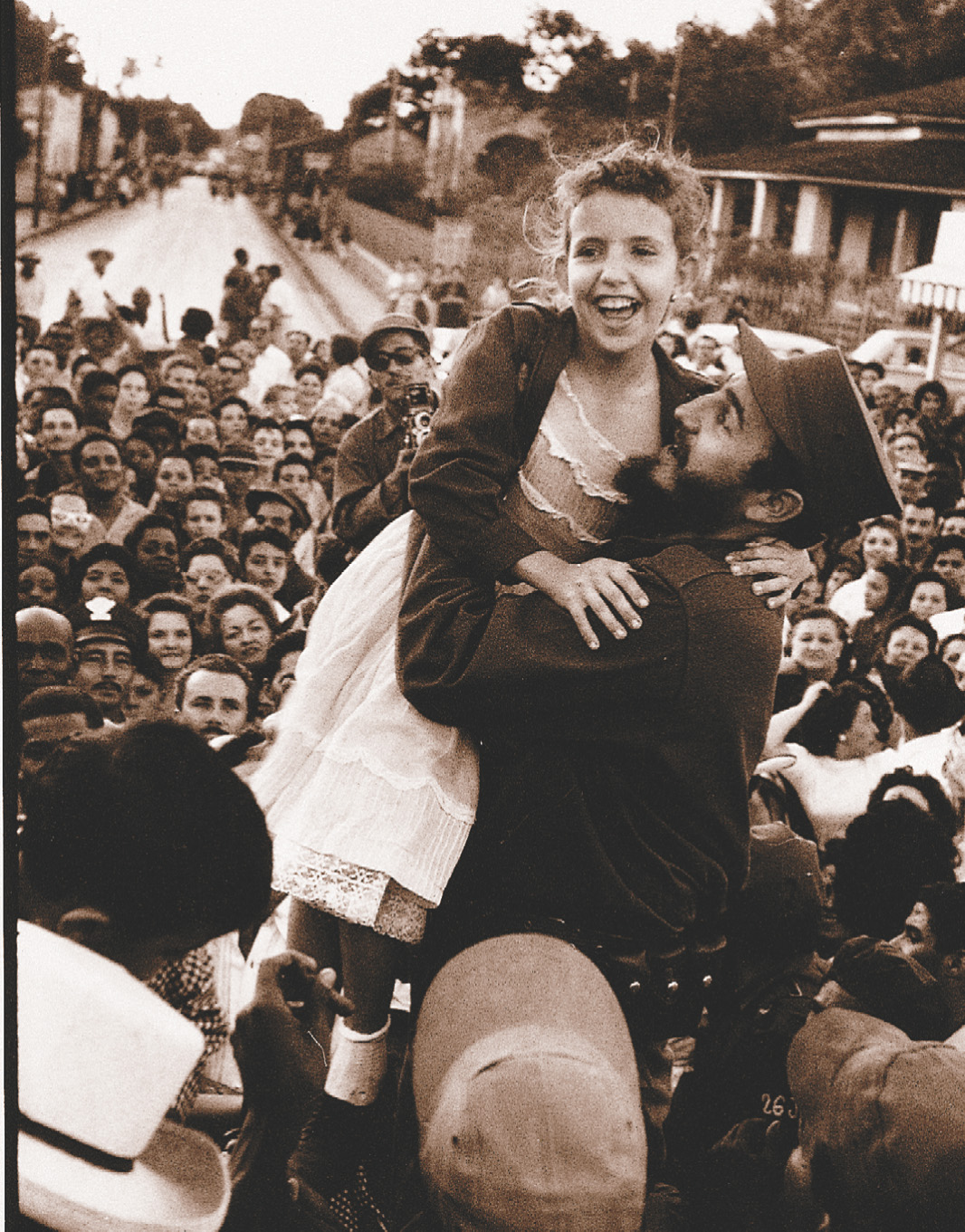 Photo: Fidel Castro holds a
smiling girl while a crowd looks on.
