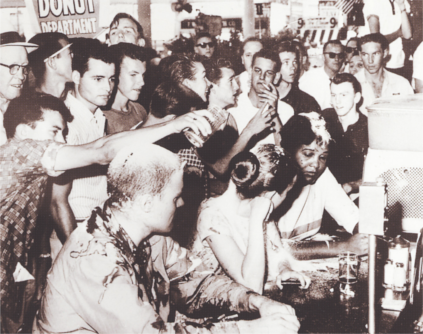 photo: a crowd of white people dumps food over African-Americans and whites sitting together at a counter.