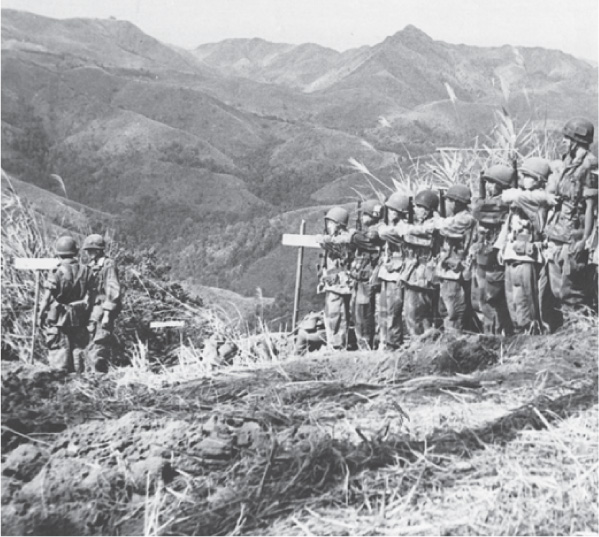photo: oldiers stand at attention in a field near mountains.