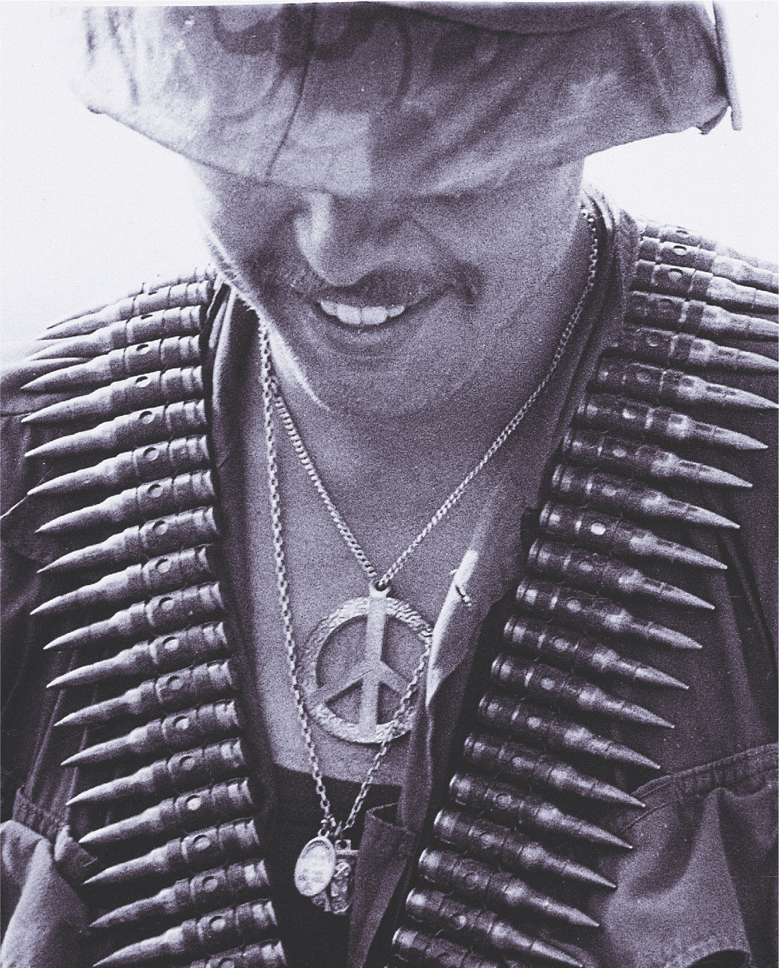 photo: a soldier wears bandoliers of bullets and a peace-sign necklace.