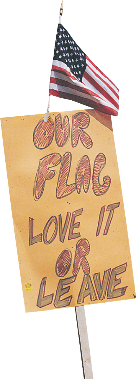 Photo: a sign below a flag reads Our flag, love it or leave.