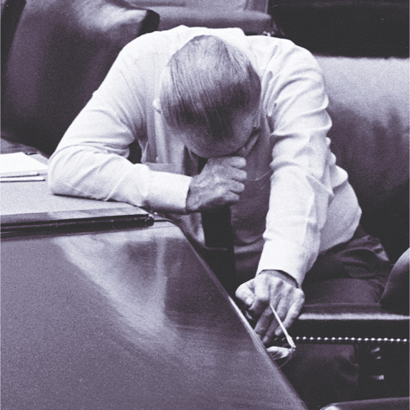 photo: Lyndon Johnson leans over, his hand held to his head.