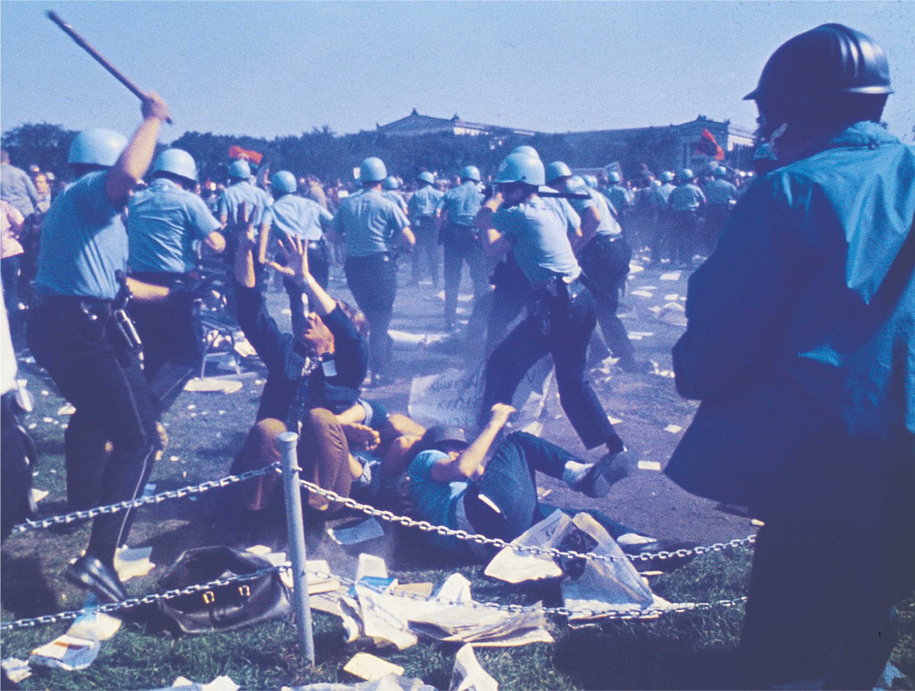 photo: police in helmets pummel protestors with clubs.