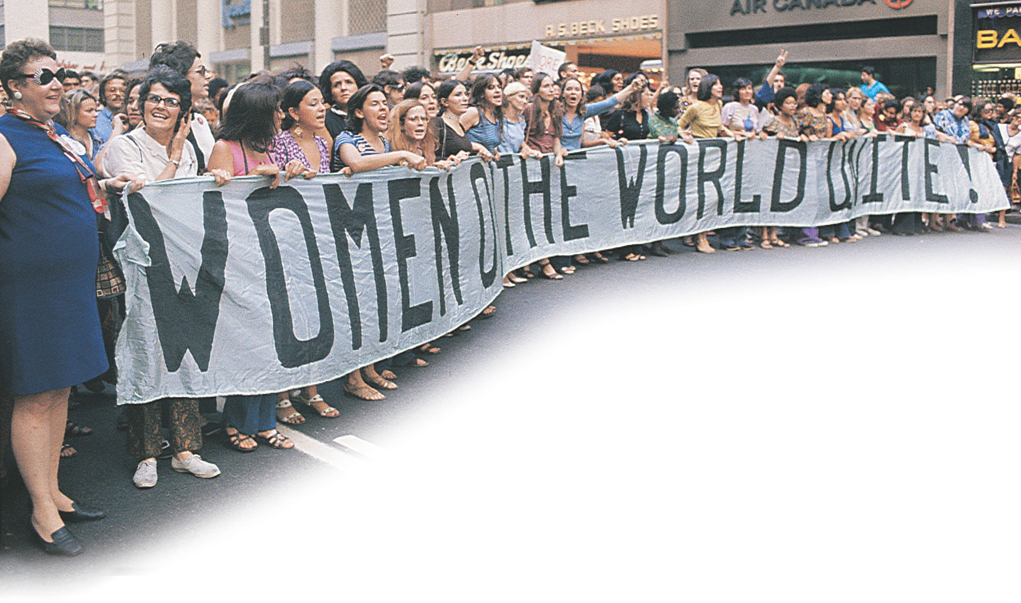 photo: women hold a huge banner that reads Women of the World Unite!
