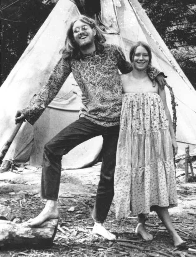 photo: a young couple stands barefoot by a tent.