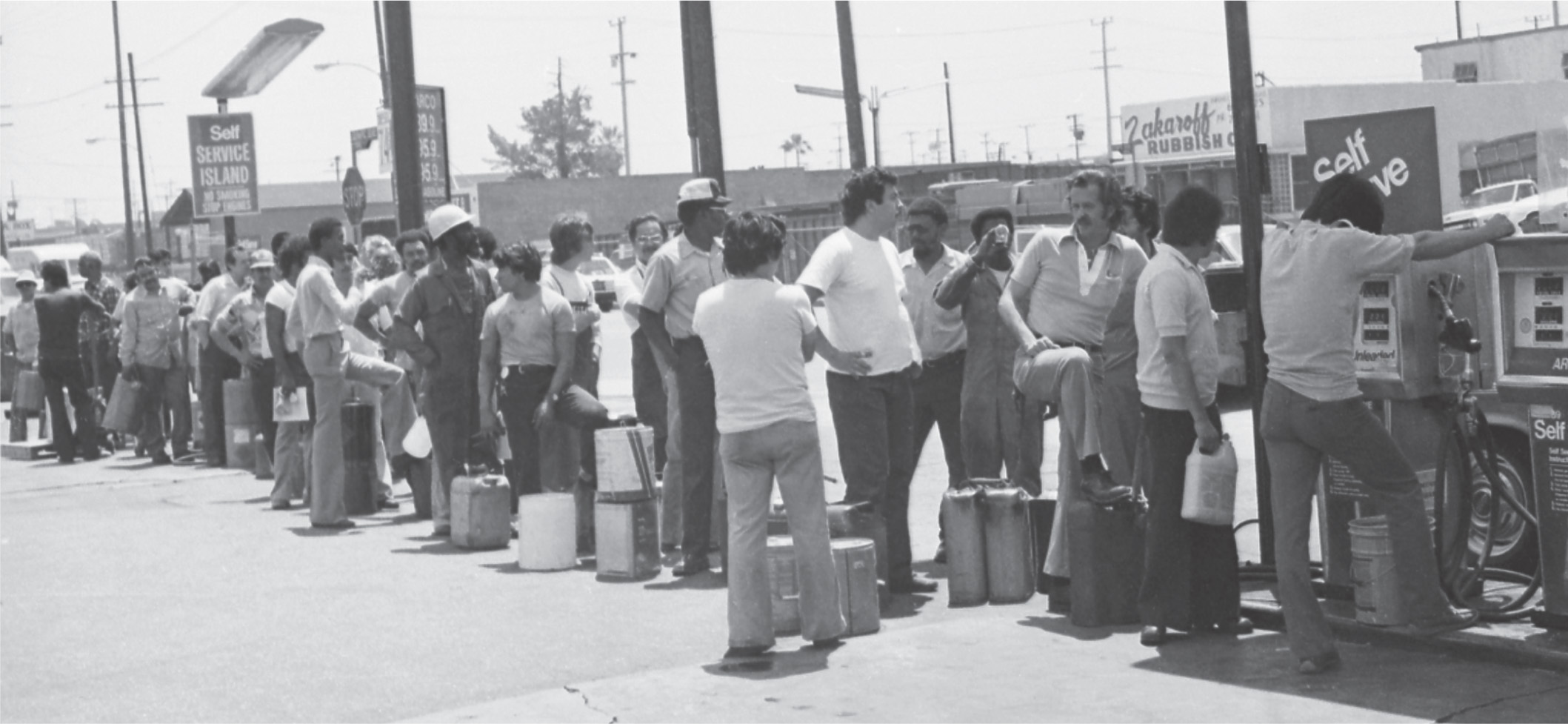 photo: people with gas cans stand in a long line at a gas station.