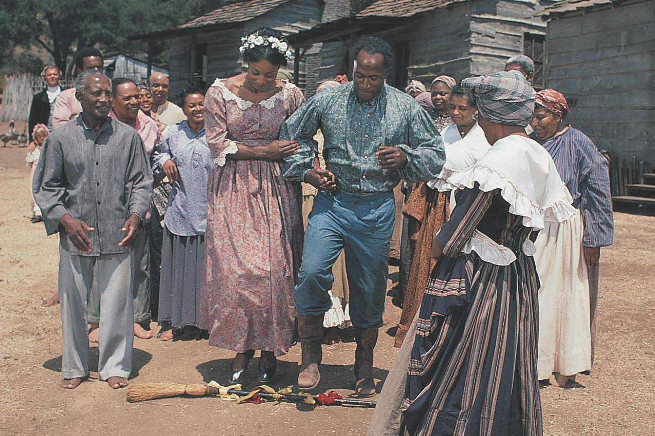 photo: in a wedding scene from Roots, a slave couple jumps over a broom together.