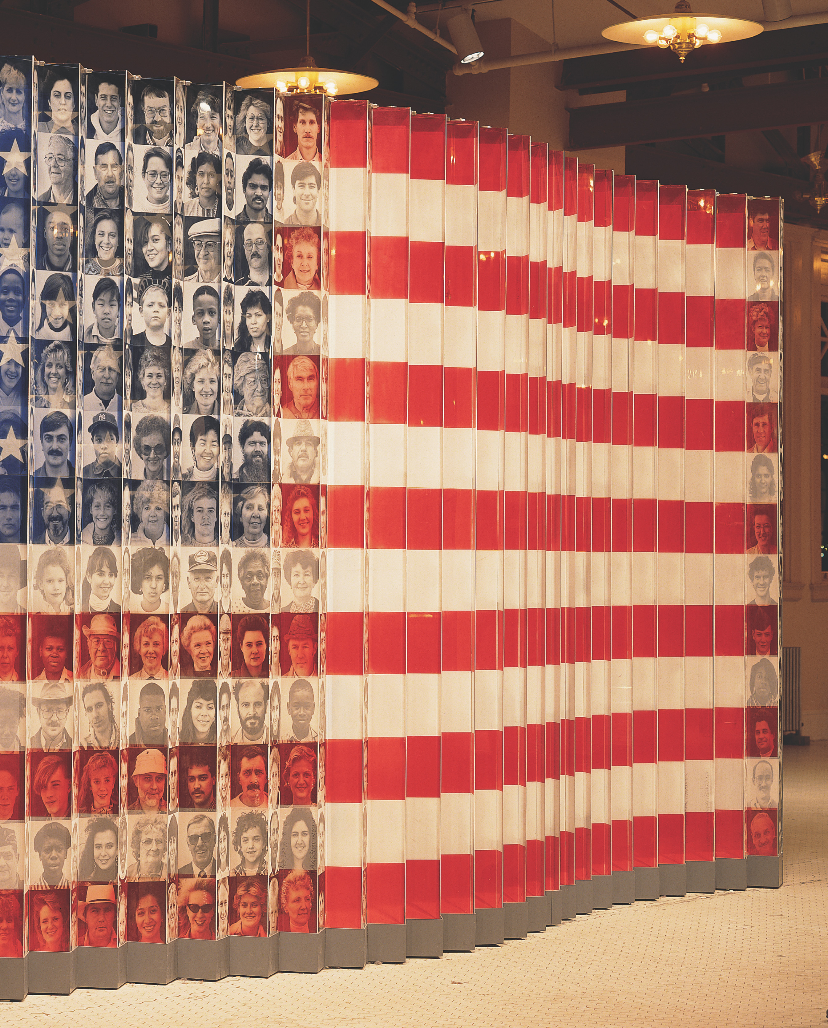a wall-sized exhibit shows faces of Americans over the stars and stripes of the American flag.