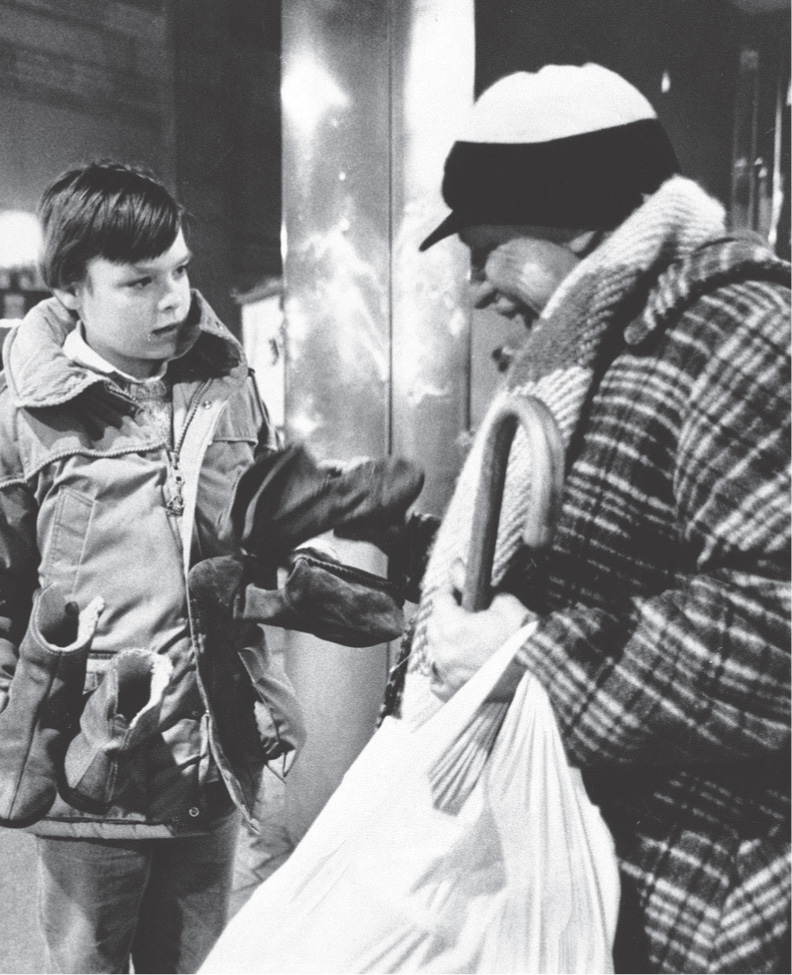 Photo: a boy hands clothes to a man in a heavy coat.