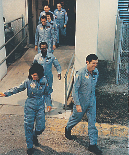 Photo: Astronauts in jumpsuits leave a building.