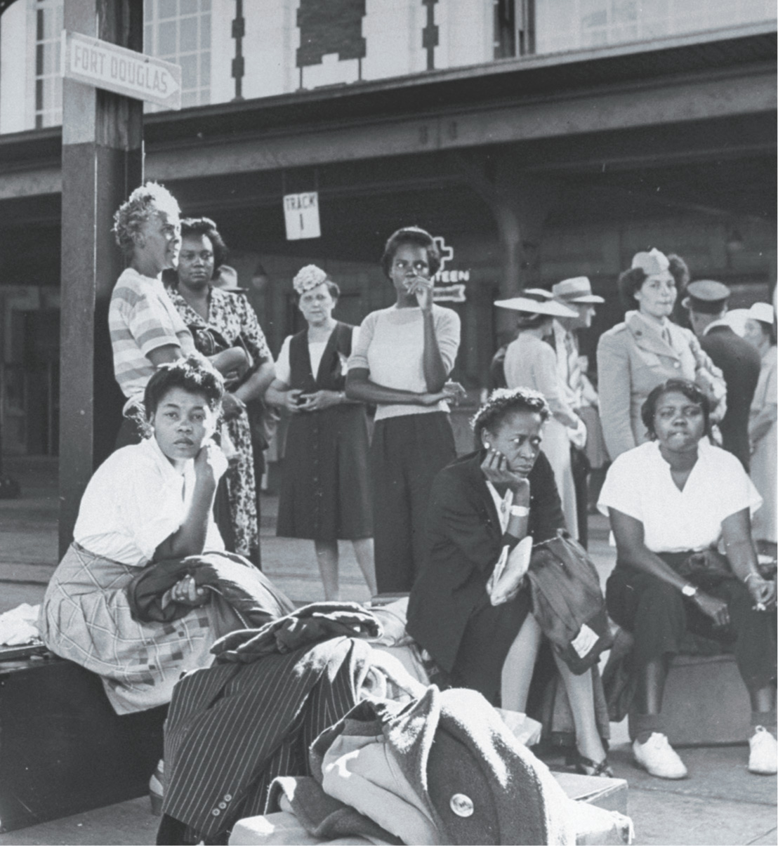 photo: African-American women wait on a sidewalk with their suitcases.