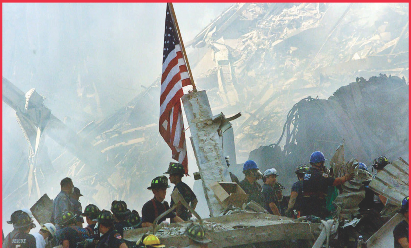 photo: An American flag rises over workers standing by a huge pile of rubble.