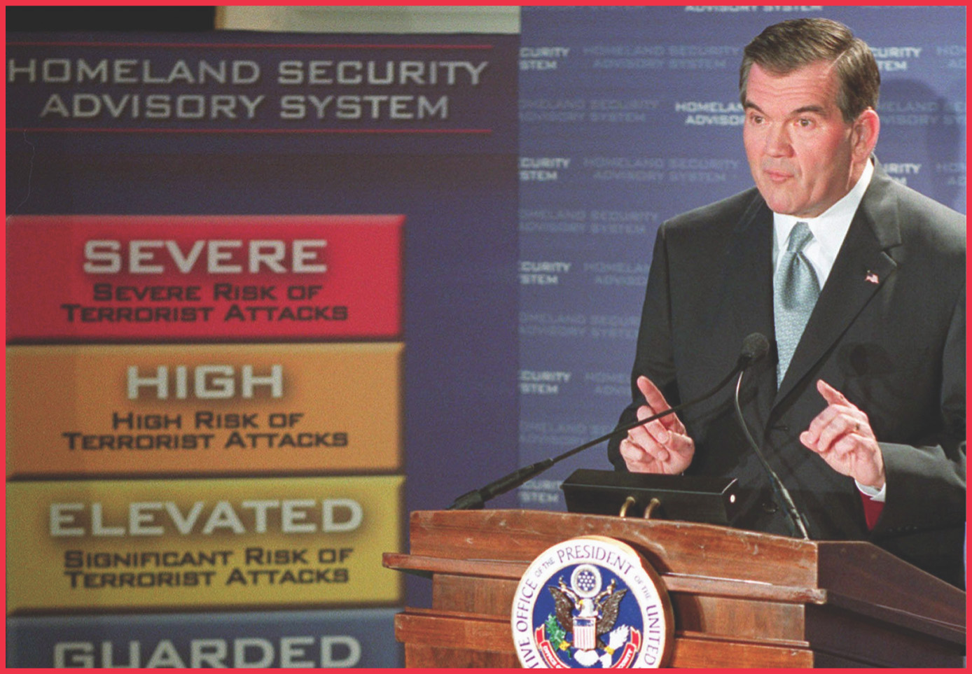 photo: Tom Ridge stands by a chart labled Homeland Security Advisory System.
