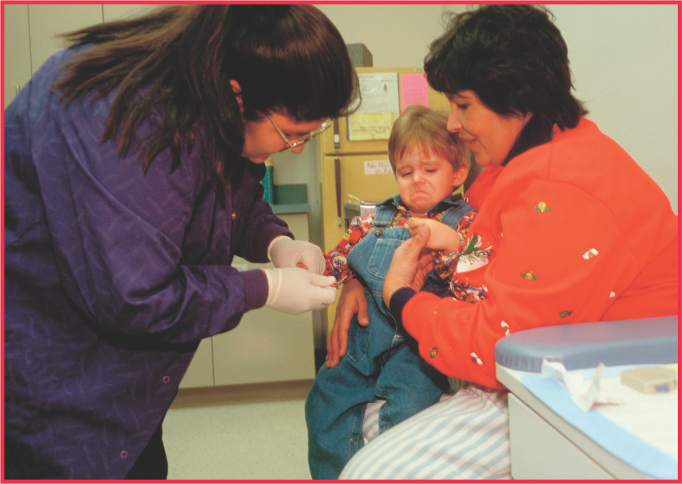 a technician takes a blood sample from a young boy.