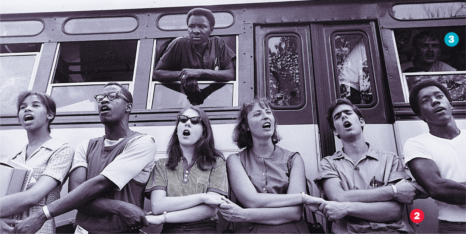 photo: young white people and African-Americans join hands and sing in front of a bus.