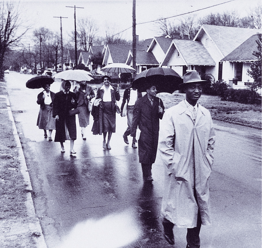 photo: African-Americans carry umbrellas as they walk down a rain-slicked street.